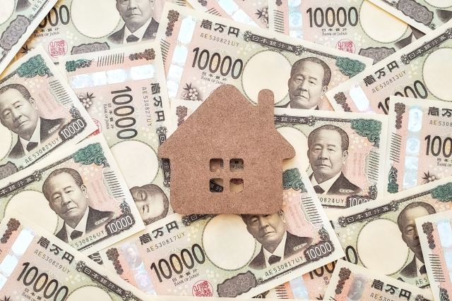 ランダムに敷かれた１万円札の中心に木でできた家の模型が置いてある画像