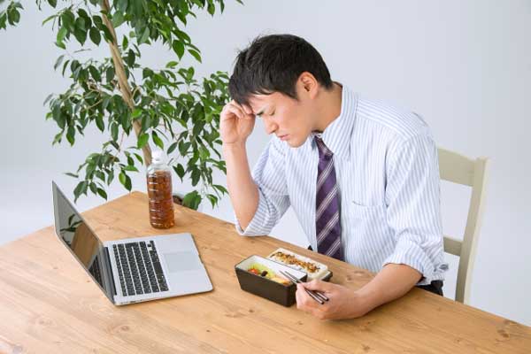 お昼ごはんを食べながら住宅ローンを組みたいと悩む会社員の画像